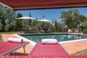 una mesa roja y sillas junto a una piscina en Villa Bellaria Lucignano, en Lucignano