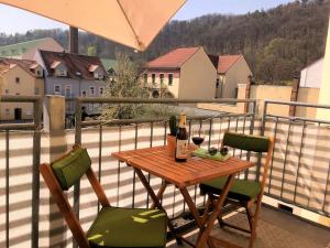 a table with a bottle of wine and two chairs on a balcony at Ferienwohnung Kurzmalweg -Balkon- in Meißen