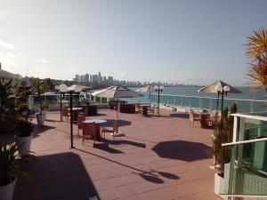 a patio with tables and chairs next to the water at Blue Sunset Flats Beira Mar - Apt 322 in João Pessoa