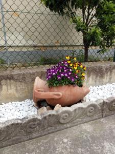um vaso de flores sentado sobre pedras num jardim em Alfi BeB em Le Torri