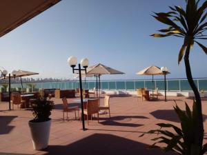 un patio con mesas y sillas y vistas al océano en Blue Sunset Flats - apt 217, en João Pessoa