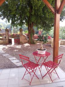 einem roten Tisch und Stühlen mit einer Topfpflanze darauf in der Unterkunft Chambre Hôte Villa Sainte Barbe in Mirecourt