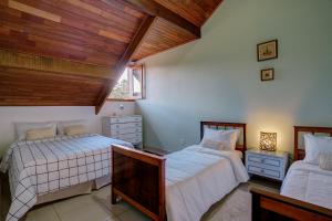 two beds in a bedroom with a wooden ceiling at Apart Central MV in Monte Verde
