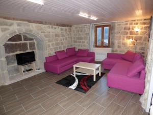 sala de estar con sofás morados y chimenea en Hameau de Gratte en Faugères in Rhone-Alpes