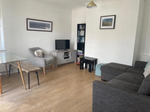 a living room with a couch and a table and a tv at Woolacombe Seaside Apartment in Woolacombe