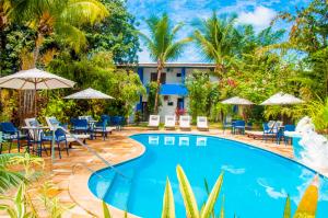 皮帕Pousada Arriba Pipa的配有桌椅和遮阳伞的度假村泳池