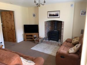 sala de estar con 2 sofás y chimenea en River Cottage en Conwy