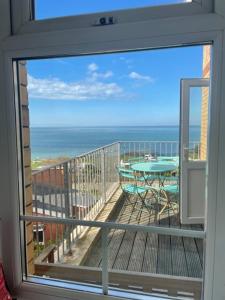 a view of a balcony with a table and the ocean at Woolacombe Seaside Apartment in Woolacombe