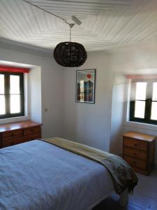 a bedroom with a blue bed and two windows at A Quinta da Colina ( Casinha ) in Castanheira de Pêra