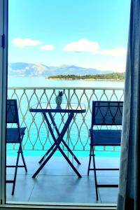 una mesa y sillas en un balcón con vistas al agua en Vidos Seaview Suite en Corfú
