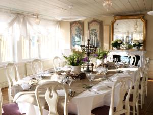 a dining room with a long table with white chairs at Gripsholms Värdshus in Mariefred