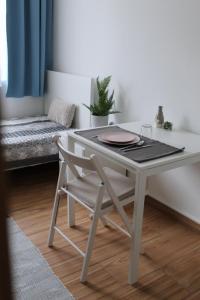 a white table and a chair with a table and a couch at Altair Airport Apartman in Vecsés