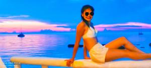 a woman in a white dress sitting on a surfboard at Clear View Resort in Koh Tao