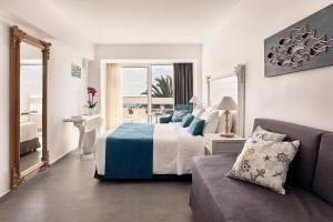um quarto de hotel com uma cama e um sofá em Tylissos Beach Hotel - Adults Only em Lerápetra
