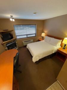 a bedroom with a bed and a desk and a window at Elkwater Lake Lodge and Resort in Elkwater