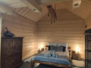 Domek na wypoczynek في تيلسز: غرفة نوم بجدران خشبية وسرير عليه تماثيل