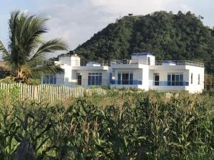 a white house in front of a fence and a mountain at MALIBU HOUSE in Salina de Rey