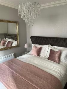 Un dormitorio con una cama grande con almohadas rosas y una lámpara de araña. en Galtres Chambers Apartment Coppergate en York