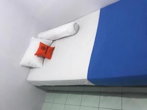a bed with white sheets and an orange pillow at KoolKost Syariah near Pelabuhan Tanjung Priok (Minimum Stay 6 Nights) in Jakarta