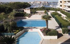 a swimming pool with palm trees and a building at studio la grande roue VUE MAGNIFIQUE in Cap d'Agde