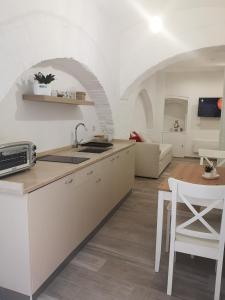 a kitchen with white cabinets and a table and a couch at Dimora San Francesco in Bevagna
