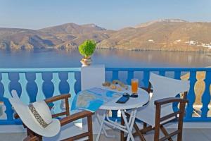 a table and chairs on a balcony with a view of the water at Nikola's Place in Astypalaia Town