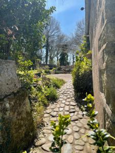 a stone pathway with flowers and a wall at An ti Bihan, Gite Breton à la campagne in Tonquédec