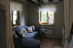 a living room with a blue couch and two windows at Całoroczny dom wakacyjny Kotkowo 93 in Kotkowo