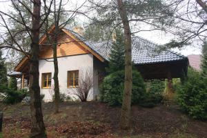 a small white house with a wooden roof at Całoroczny dom wakacyjny Kotkowo 93 in Kotkowo