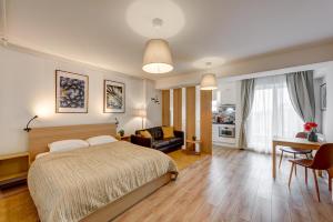 Bucharest Airport Suites & Villas في أوتوبيني: غرفة نوم مع سرير وغرفة معيشة