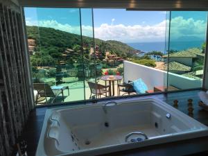 a bath tub in a room with a large window at Hotel Experience João Fernandes in Búzios
