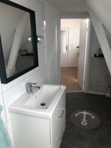 a white bathroom with a sink and a mirror at Marktblick in Norden