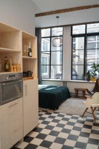 a room with a kitchen with a bed and windows at Steeg 8 in Dordrecht