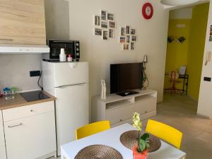a kitchen with a table and a refrigerator and a tv at Alleria Holiday Home in Salerno