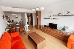 a living room with an orange couch and a table at Ski IN-OUT Apartmán Donovaly in Donovaly