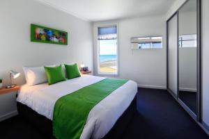 een slaapkamer met een groot bed met groene kussens bij Penguin Waterfront Escape in Penguin