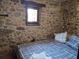 1 dormitorio con 1 cama azul en una pared de piedra en Casa Cristina, en Miranda del Castañar