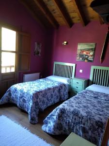 two beds in a room with purple walls at Casa Llayo in Aliezo