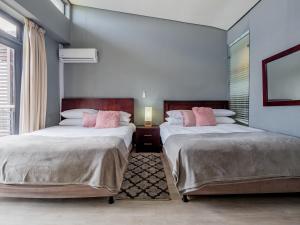 1 dormitorio con 2 camas y almohadas rosas en Point Bay - Super Stylish for Less, en Durban