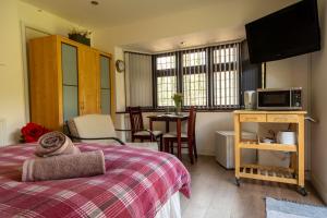 Schlafzimmer mit einem Bett, einer Mikrowelle und einem Tisch in der Unterkunft The Mills Guesthouse Hatfield in Hatfield