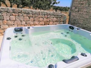 uma banheira de hidromassagem em frente a uma parede de pedra em Il Baglio di Kharrub rural guest house em Pozzallo