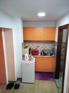 eine kleine Küche mit orangefarbenen Schränken und einem Waschbecken in der Unterkunft Apartman 1 in Vrnjačka Banja