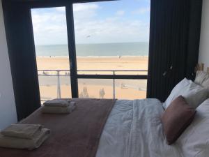 a bedroom with a bed and a view of the beach at Luxury Seaview Apartment with free private garage in Ostend