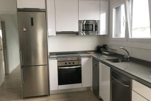 a kitchen with a stainless steel refrigerator and a sink at Apartamento Ático Miramar, Luanco in Luanco