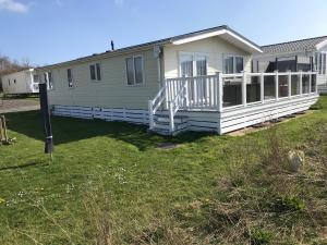 2 Bedroom Luxury Lodge, OG30, Shanklin, Isle of Wight في شانكلين: منزل متنقل مع شرفة على ساحة