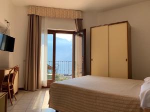 een slaapkamer met een bed en een glazen schuifdeur bij Villa Belvedere Hotel in Limone sul Garda