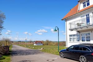 a black car parked next to a white house at DEB 040 Ferienwohnung Jasmund in Neddesitz