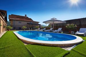 a swimming pool in a yard with chairs and an umbrella at AquaLux 2 in Soko Banja