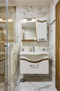 a white bathroom with a sink and a shower at AquaLux 2 in Soko Banja