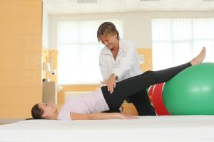 a woman playing with a child on a fitness ball at Hotel International in Baile Felix